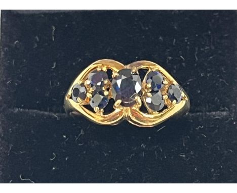 A seven stone sapphire ring with open work setting. In gold marked 750. 4g gross. Size O.