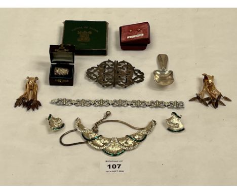 A small quantity of costume jewellery with a silver nurse's buckle, a cased silver thimble, a George V silver caddy spoon etc