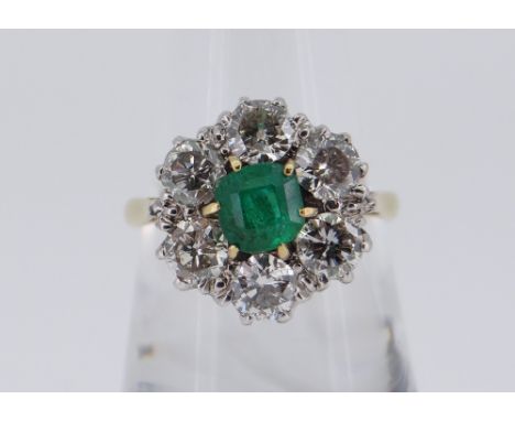 18CT GOLD EMERALD &amp; DIAMOND CLUSTER RING, the central emerald (0.5 x 0.5cms) surrounded by six diamonds approximately 0.2