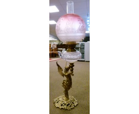 Late 19th/early 20th Century oil lamp having facet cut clear glass reservoir above a brass winged figural column, on pierced 