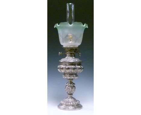 Silvered metal oil lamp having allover Neo-classical decoration in relief and with a green glass shade (converted)   Conditio