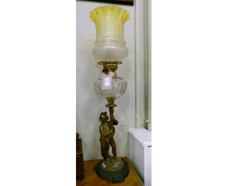 Late 19th/early 20th Century oil lamp having clear cut glass reservoir supported by a gold painted cast metal figure of a man