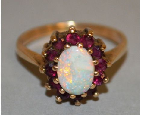 AN OPAL AND RUBY CLUSTER RING set in yellow gold.