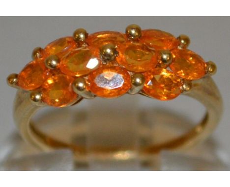 A TEN STONE ORANGE DRESS RING set in 9ct gold.