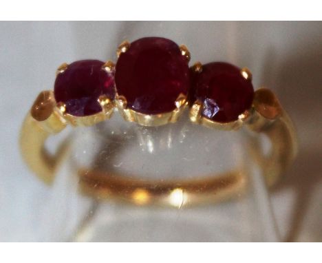 A THREE STONE RUBY RING set in 22ct yellow gold.