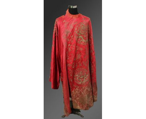 AN EARLY 20TH CENTURY CHINESE RED GROUND SILK ROBE, decorated in gilt thread with dragon roundels, bats, Shou symbols, cloud 
