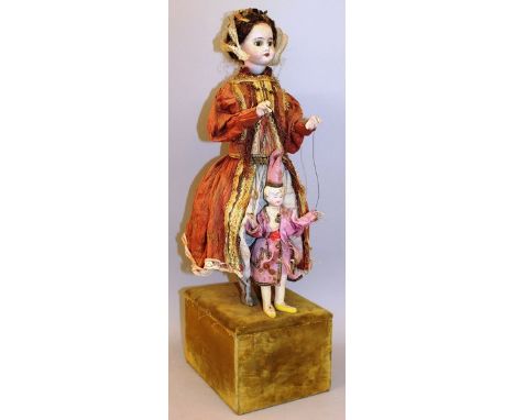 AN UNUSUAL FRENCH STANDING AUTOMATON PORCELAIN DOLL modelled in a period dress holding a bisque porcelain puppet, upon a squa