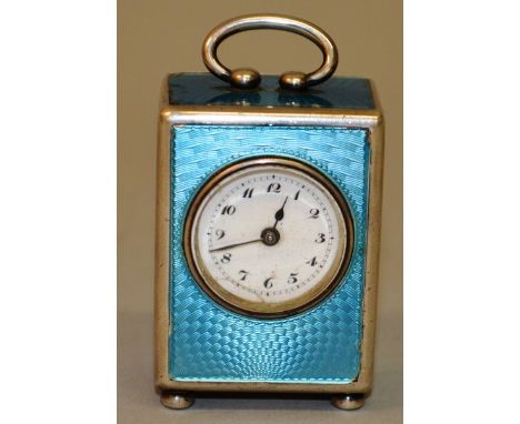 A SMALL EDWARDIAN BLUE ENAMEL AND .925 SILVER CARRIAGE CLOCK with carrying handle on bun feet 2.25ins high.