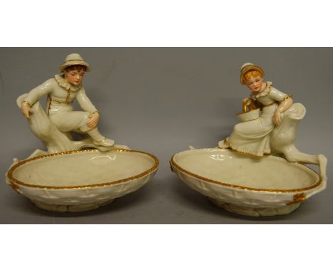 A ROYAL WORCESTER FINE PAIR OF KATE GREENAWAY FIGURAL COMPORTS depicted as a boy and girl both holding large open baskets.