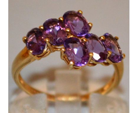 A SIX STONE AMETHYST CROSSOVER RING set in 9ct gold.