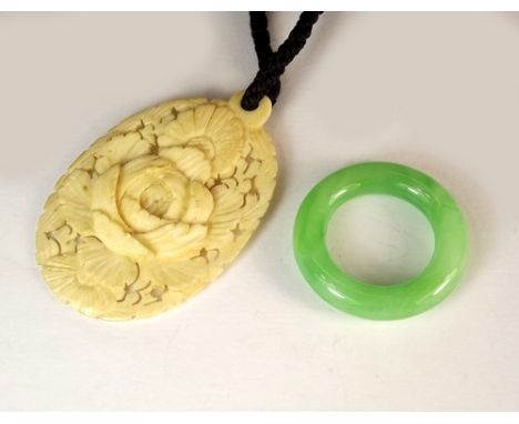 JADE ETC.
An oriental pale green jade roundel & an oriental carved ivory pendant, the back with a carved character mark.