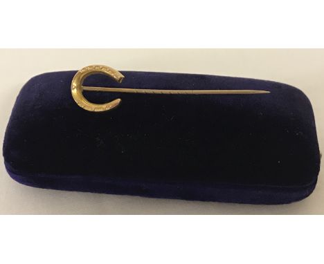 A vintage boxed 9ct gold stickpin with horseshoe shaped pendant. Pin marked 9ct; complete with original blue velvet presentat