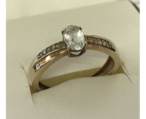 A 9ct gold aquamarine and moissanite dress ring. Central oval cut aquamarine with 5 small cut moissanite stones to each shoul