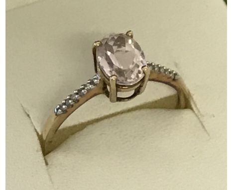 A 9ct gold morganite and diamond dress ring. Central oval cut morganite stone with 6 small diamond to each shoulder. Size R 1