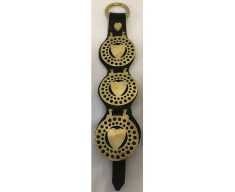 A vintage leather strap containing 3 love heart horse brasses.  Approx. 44cm long.