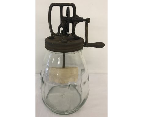A vintage glass butter churn with metal lid and wooden paddle.  