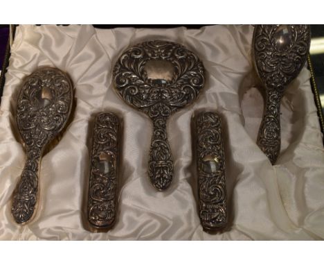 A cased five piece silver dressing table set having embossed mask, bird and scroll decoration, Birmingham 1966, W I Broadway 