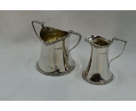 An Edwardian silver cream jug and sugar bowl of plain waisted form having moulded decoration to rim and bases, London 1907/09