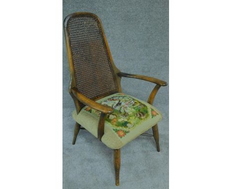 A mid 20th century beech framed armchair with caned back and stuffover tapestry seat. H.100cm 