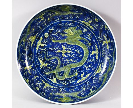 A CHINESE BLUE GROUND PORCELAIN DRAGON DISH, the centre painted with a dragon and the pearl of wisdom amongst stylised clouds