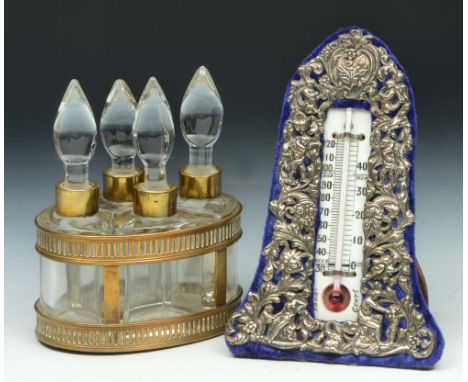 A FRENCH GILT METAL OVAL SCENT BOTTLE STAND, fitted with four shaped glass bottles and stoppers, 14cm high; and a silver moun