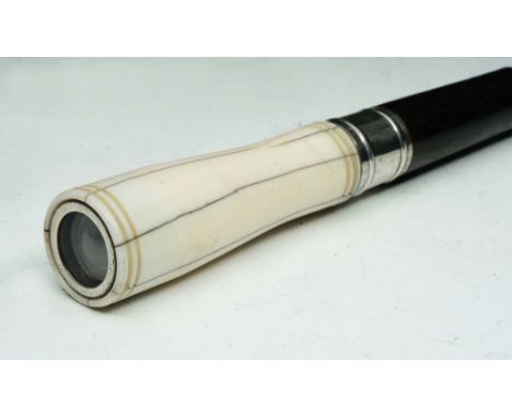 AN EBONY WALKING STICK with ivory 'eye' handle and silver metal ferrule, 90.2cm long