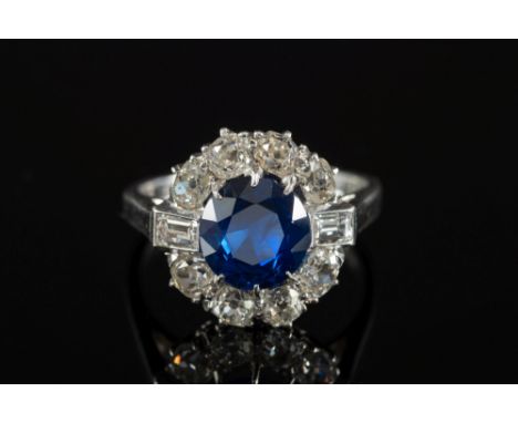 A sapphire and diamond circular cluster ring: with central round sapphire approximately 7.9mm diameter, claw-set within a sur