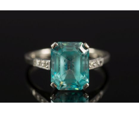 A rectangular blue zircon single-stone ring: approximately 10mm long x 7.8mm wide x 5.2mm deep, between diamond three stone s