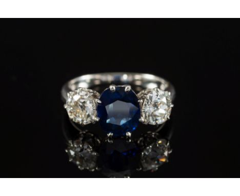 A sapphire and diamond three-stone ring: with central oval sapphire approximately 7.8mm long x 6.7mm wide, between round old 