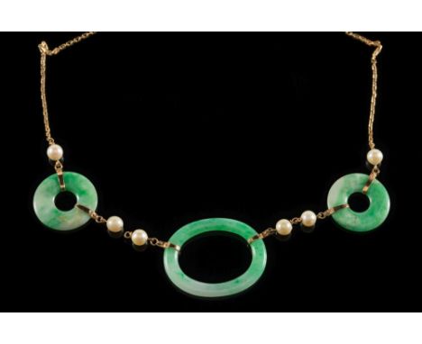 A green jade and cultured pearl necklace: with central oval, mottled pale green jade 42mm long, between jade discs, joined by