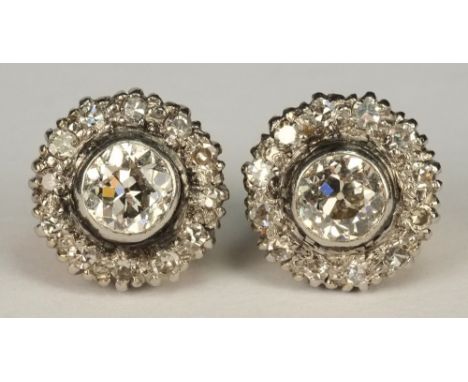 A pair of diamond mounted circular cluster earrings:, each with a circular brilliant-cut diamond approximately 0.25ct, in rub