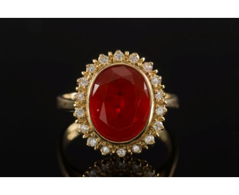 An 18ct gold, fire opal and diamond oval cluster ring:, the oval fire opal within a surround of circular, brilliant-cut diamo