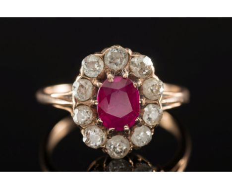 A ruby and diamond oval cluster ring:, the oval ruby within a surround of circular, old brilliant-cut diamonds, ring size 'K 