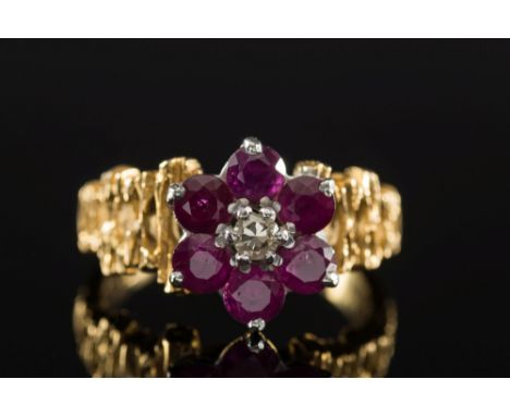 A ruby and diamond cluster ring: with central brilliant-cut diamond claw-set within a surround of round rubies, the shank sta