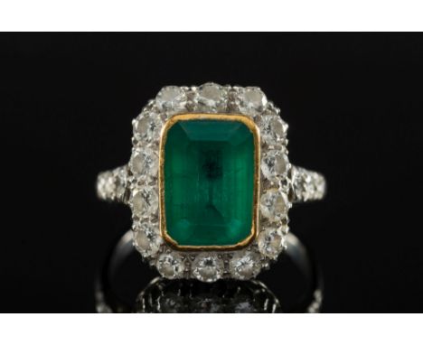 An emerald and diamond rectangular cluster ring:, the rectangular emerald approximately 10mm long x 8mm wide x 4.3mm deep, wi