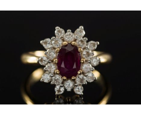 An 18ct gold, ruby and diamond oval cluster ring:, the central, oval ruby within a surround of circular, brilliant-cut diamon