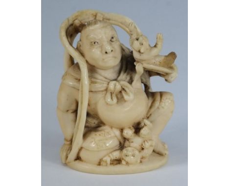 A Japanese carved ivory netsuke depicting a man holding a demon on a leaf with another at his feet:, inscribed to base, 6cm h