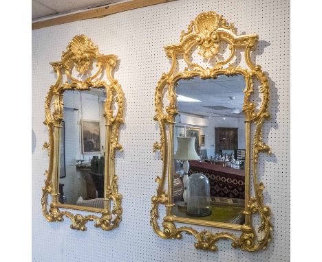 WALL MIRRORS, a pair, Chippendale style gilt, each with a shell surmount and leaf and scroll decoration, 69cm W x 126cm H. (2