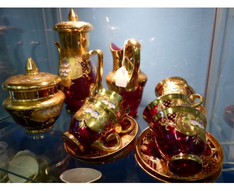 A Quantity of Ruby Hand Painted Gilt Bohemian Glass with Floral Spray, comprising six cups and saucers, coffee pot, milk jug 