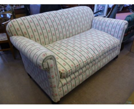 An Antique Two Seater Sofa, with cream and floral upholstery on turned feet.