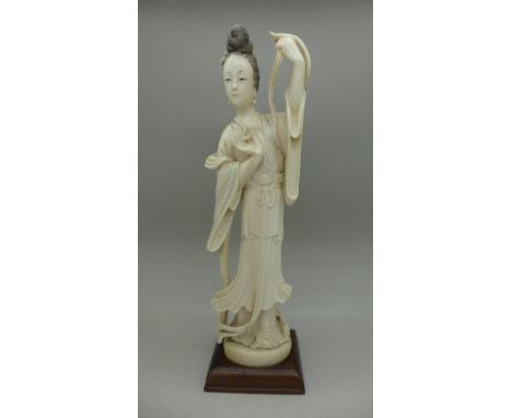 An early 20th Century carved ivory figure of a lady, on a wooden stand, 22cm