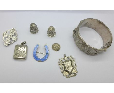 A Victorian silver locket, a silver and blue enamel horseshoe brooch, a silver buckle bangle, two silver thimbles, etc., 75g