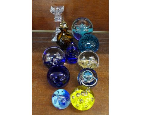 Nine glass paperweights, a glass candlestick and bottle