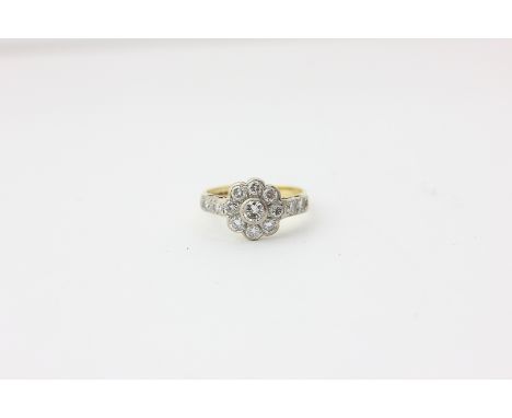 A nine stone diamond cluster ring with pairs of diamonds to each shoulder in 18ct white and yellow gold