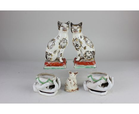 A pair of Staffordshire pottery models of cats seated on rectangular cushion bases, 17.5cm high, and a miniature glazed potte