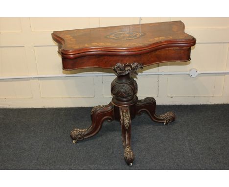 An inlaid walnut card table, the serpentine fold over top with floral and scroll decoration, with carved baluster stem in fou