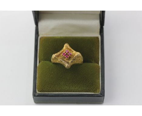 An 18ct yellow gold and ruby ring claw set with a central group of four small rubies on a textured mount 8.2g gross 