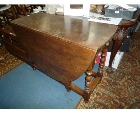 An Oak gate leg Dining Table having turned legs, trinket drawer, the top 42" x 16 5/8" extending to an oval 60", approx. 29 1