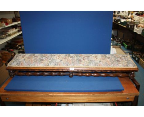 A long, low Footstool/Stool on six turned legs and stretchers, upholstered with stylised foliage and floral decorated fabric,