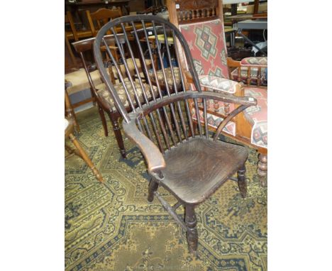 A solid Elm wood seated Kitchen Elbow Chair having stick back, turned legs and stretchers (some damage/distress).